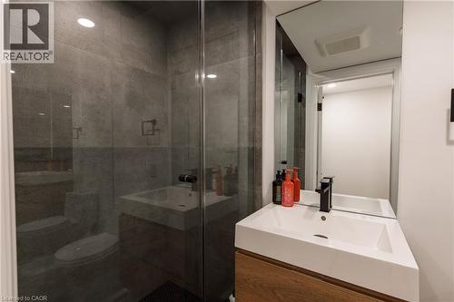 Contemporary bathroom featuring a floating wood-finish vanity with an integrated white sink, matte black faucet, and a large mirrored wall - 916 Steepleridge Court, Kitchener, ON - Indoor Photo Showing Bathroom