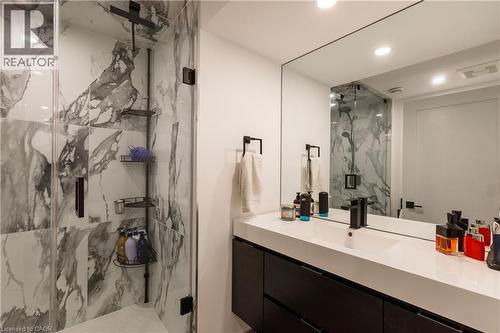 Sleek bathroom featuring a spacious glass-enclosed shower with large format marbled tile surround and a rainfall showerhead - 916 Steepleridge Court, Kitchener, ON - Indoor Photo Showing Bathroom