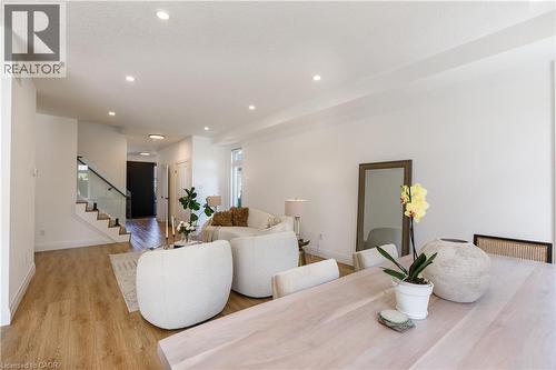 Open-concept living area featuring wood-finish flooring, recessed lighting, and a modern glass staircase railing - 916 Steepleridge Court, Kitchener, ON - Indoor Photo Showing Living Room