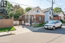 Brick and siding exterior featuring a covered porch, front yard landscaping, a driveway, and a wood privacy fence - 252 Beechwood Avenue, Hamilton, ON  - Outdoor With Facade 