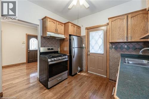 Kitchen featuring wood-finish flooring, stainless steel range, stainless steel refrigerator, and wood cabinetry - 252 Beechwood Avenue, Hamilton, ON - Indoor Photo Showing Kitchen With Double Sink