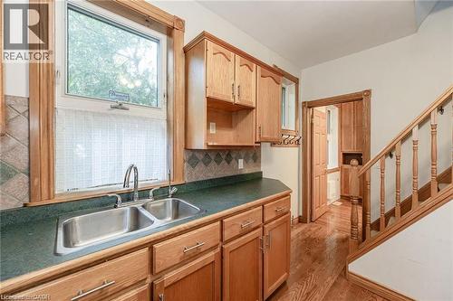 Kitchen area featuring wood cabinetry with silver hardware, a dual-basin stainless steel sink, and a dark countertop - 252 Beechwood Avenue, Hamilton, ON - Indoor Photo Showing Kitchen With Double Sink