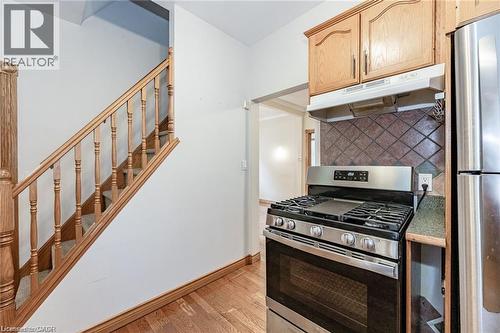 Stainless steel range with a gas cooktop, tile backsplash, wood-finish cabinetry, and wood-finish flooring - 252 Beechwood Avenue, Hamilton, ON - Indoor Photo Showing Kitchen