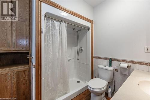 Bathroom featuring a stand-up shower with a white surround, white toilet, and wood-finish flooring - 252 Beechwood Avenue, Hamilton, ON - Indoor Photo Showing Bathroom
