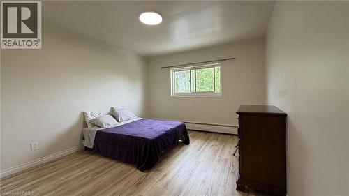 Spacious room featuring wood-finish flooring, a window offering natural light, and a ceiling-mounted light fixture - 206 Indian Road, Kitchener, ON - Indoor Photo Showing Bedroom