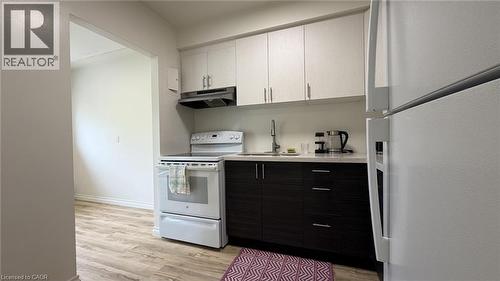 Kitchen featuring two-tone cabinetry with light upper and dark lower units, a white electric range, and a white refrigerator - 206 Indian Road, Kitchener, ON - Indoor Photo Showing Kitchen