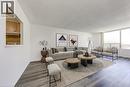 Spacious living area featuring large windows, wood-finish flooring, and a pass-through window opening to the kitchen - 1270 Maple Crossing Boulevard Unit# 1705, Burlington, ON  - Indoor Photo Showing Living Room 