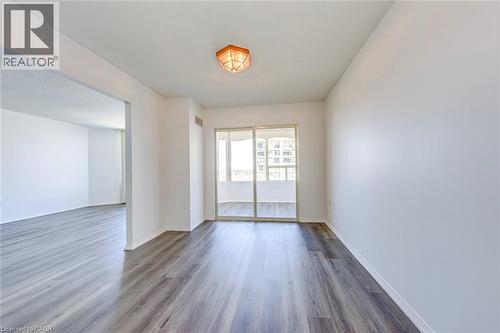 Spacious interior featuring wood-finish flooring, white walls, and a recessed ceiling light - 1270 Maple Crossing Boulevard Unit# 1705, Burlington, ON - Indoor Photo Showing Other Room