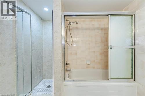 Bathroom featuring a tiled walk-in shower with a glass enclosure and an additional bathtub with a sliding frosted glass door - 1270 Maple Crossing Boulevard Unit# 1705, Burlington, ON - Indoor Photo Showing Bathroom