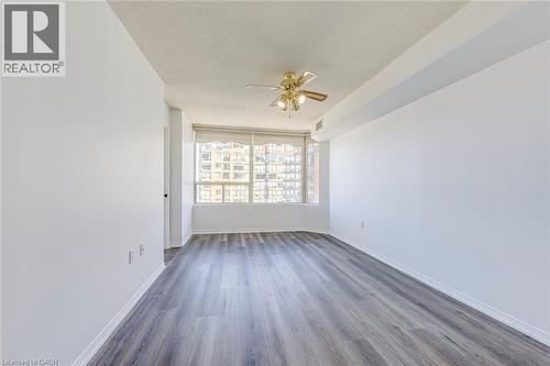 Spacious room with wood-finish flooring, white walls, and a large window with white blinds - 1270 Maple Crossing Boulevard Unit# 1705, Burlington, ON - Indoor Photo Showing Other Room