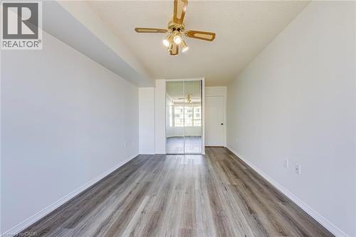 Expansive room featuring wood-finish flooring, white painted walls, a sliding mirrored closet, a recessed ceiling beam, and a ceiling fan with integrated lighting - 1270 Maple Crossing Boulevard Unit# 1705, Burlington, ON - Indoor Photo Showing Other Room