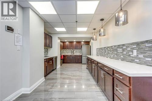 Modern kitchen featuring a mosaic tile backsplash, dark wood cabinetry, white countertops, and stainless steel appliances - 1270 Maple Crossing Boulevard Unit# 1705, Burlington, ON - Indoor Photo Showing Other Room