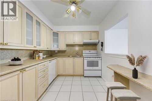 Kitchen featuring extensive cabinetry, tile flooring, a built-in oven range, and a breakfast bar with seating - 1270 Maple Crossing Boulevard Unit# 1705, Burlington, ON - Indoor Photo Showing Kitchen