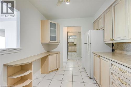 Kitchen featuring white square tile flooring, light-toned cabinetry, light-toned countertops, and a full-size white refrigerator - 1270 Maple Crossing Boulevard Unit# 1705, Burlington, ON - Indoor Photo Showing Kitchen