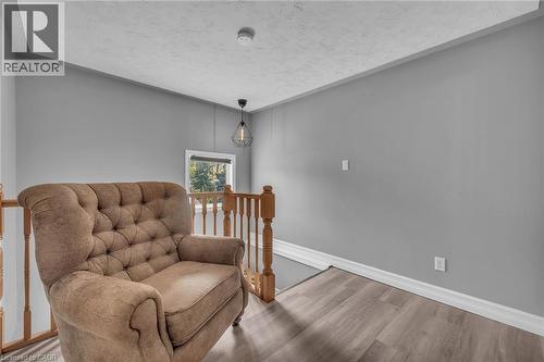 Upper-level landing featuring wood-finish flooring, light gray walls, a window providing natural illumination, white baseboards, and a contemporary pendant light fixture - 270 Erie Boulevard, Long Point, ON - Indoor