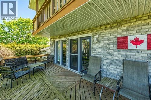 Spacious outdoor deck featuring wood flooring with a geometric pattern, direct access through two glass-paneled doors, and an overhead balcony - 270 Erie Boulevard, Long Point, ON - Outdoor With Deck Patio Veranda With Exterior