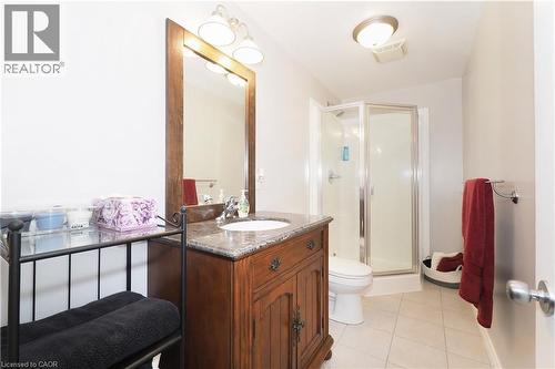 lower level Bathroom featuring a wood-finish vanity with a stone countertop, an integrated sink, and a framed mirror,  complete with a separate  shower - 565 Springwater Drive, Waterloo, ON - Indoor Photo Showing Bathroom