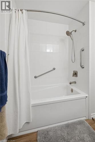 Bathtub with white tile surround, brushed nickel fixtures, and safety grab bars - 1862 Briarwood Drive, Cambridge, ON - Indoor Photo Showing Bathroom