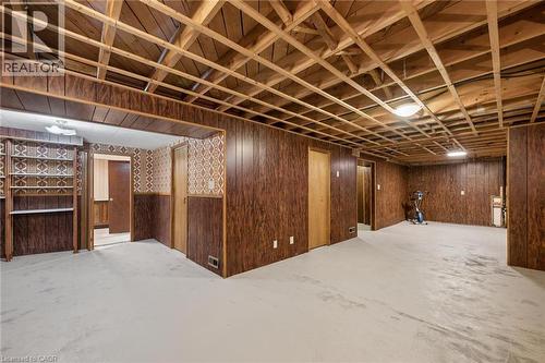 Spacious room featuring exposed ceiling joists, wood-look paneling, and light-colored flooring - 1862 Briarwood Drive, Cambridge, ON - Indoor Photo Showing Basement