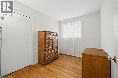 Bright interior space featuring wood-finish flooring, a white bi-fold closet, and a window with sheer curtains - 1862 Briarwood Drive, Cambridge, ON - Indoor