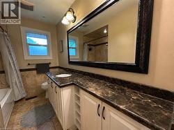 Spacious vanity featuring a dark patterned countertop, white cabinetry with dark hardware, and an oversized decorative mirror - 