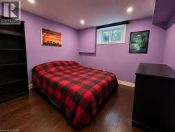Recessed lighting illuminates this room, featuring wood-finish flooring and a window with a roller shade - 