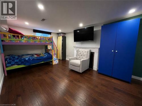 Recessed lighting illuminates the room featuring wood-finish flooring, a built-in fireplace with a white mantel, and a mounted television - 917 Orpha Street, Burlington, ON - Indoor