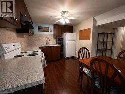 Kitchen featuring wood-finish flooring, dark wood cabinetry, a white electric range, and a white refrigerator - 