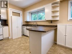 Kitchen featuring white cabinetry, a brown speckled countertop, and light-toned tile flooring - 