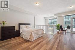 Spacious room featuring wood-finish flooring, high ceilings with flush mount lighting, and a white railing overlooking a lower level - 