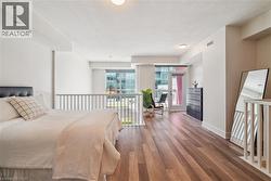 Open-concept living area featuring high ceilings, wood-finish flooring, and a private balcony with glass doors - 