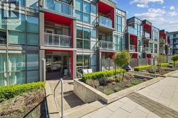 Contemporary townhome exterior featuring expansive window walls, individual balconies with glass railings, and a bold red architectural accent - 