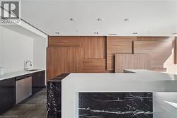 Contemporary kitchen featuring a prominent island with a black veined stone base and a white countertop - 