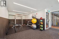 Dedicated fitness area featuring rubberized flooring, integrated ceiling lighting, and a textured wall finish - 