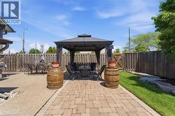 Outdoor entertaining area featuring a central gazebo with a hardtop roof and privacy curtains - 