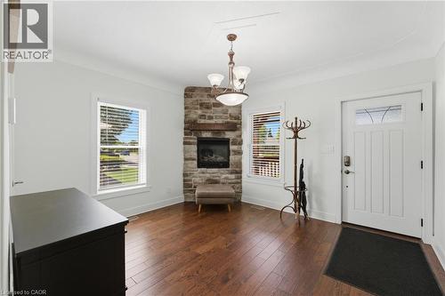 Entryway featuring a corner stone fireplace with a wood mantle, rich wood-finish flooring, and crown molding - 69 Nash Road S, Hamilton, ON - Indoor With Fireplace