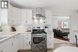 Kitchen featuring white shaker-style cabinetry, stainless steel appliances, a subway tile backsplash, and light-toned countertops - 