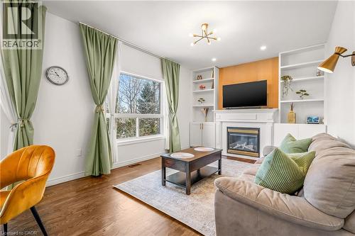 Living area featuring wood-finish flooring, a large window, fireplace with white mantel, built-in shelving, and recessed lighting - 12 Buman Court, Barrie, ON - Indoor Photo Showing Living Room With Fireplace