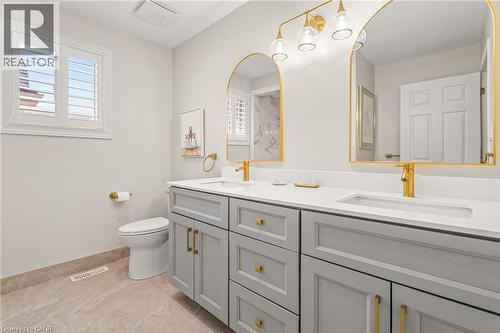 Bathroom featuring a dual vanity with light gray cabinetry, integrated white countertops, and gold-finish fixtures - 12 Buman Court, Barrie, ON - Indoor Photo Showing Bathroom