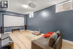 Entertainment room featuring a large projection screen, a ceiling-mounted projector, and light wood-finish flooring - 