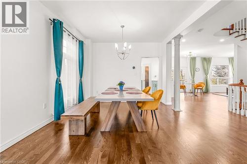 Spacious dining area featuring wood-finish flooring, white baseboards, and a modern chandelier - 12 Buman Court, Barrie, ON - Indoor Photo Showing Dining Room