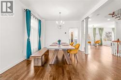 Spacious dining area featuring wood-finish flooring, white baseboards, and a modern chandelier - 