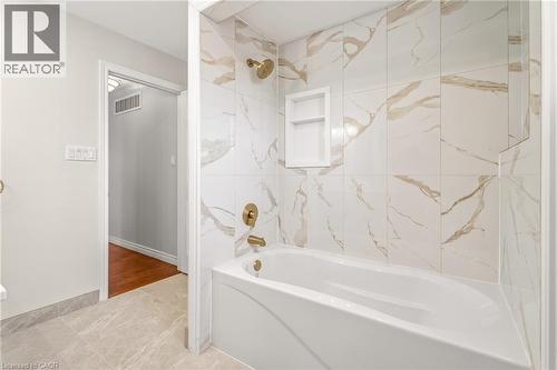 White porcelain bathtub with brass fixtures, complemented by large format wall tiling featuring brown veining and a built-in shower niche - 12 Buman Court, Barrie, ON - Indoor Photo Showing Bathroom