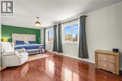 Spacious room with polished wood-finish flooring, a feature wall, and two large windows - 12 Buman Court, Barrie, ON - Indoor Photo Showing Bedroom