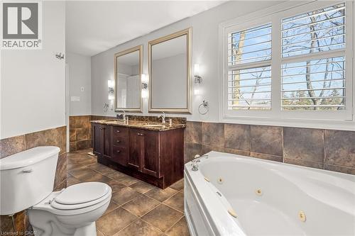 Bathroom featuring a jetted soaking tub, dual vanity with framed mirrors, stone countertop, and tile flooring - 12 Buman Court, Barrie, ON - Indoor Photo Showing Bathroom