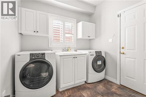 Dedicated laundry room featuring a utility sink with a cabinet base, wall-mounted cabinetry, and tile flooring - 12 Buman Court, Barrie, ON - Indoor Photo Showing Laundry Room