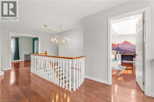 Upper landing featuring wood-finish flooring, a white spindle railing with a wood handrail, and a gold-tone chandelier - 12 Buman Court, Barrie, ON - Indoor Photo Showing Other Room