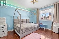 Hardwood flooring and light blue walls featured in a bedroom with a large window and crown molding - 