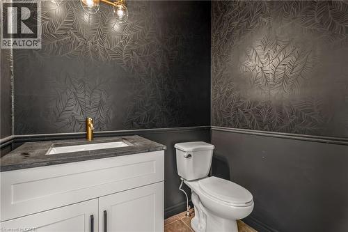 Powder room featuring a white vanity with dark hardware, a single-basin sink, and a gold-tone faucet - 12 Buman Court, Barrie, ON - Indoor Photo Showing Bathroom