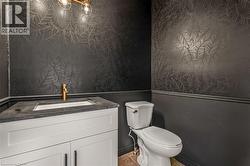 Powder room featuring a white vanity with dark hardware, a single-basin sink, and a gold-tone faucet - 